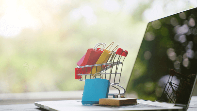 Laptop with mini shopping cart and shopping bags on top
